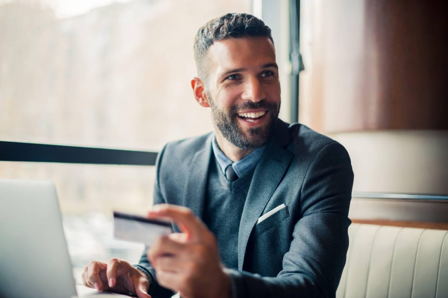 Businessman sitting holding a credit card near a window
